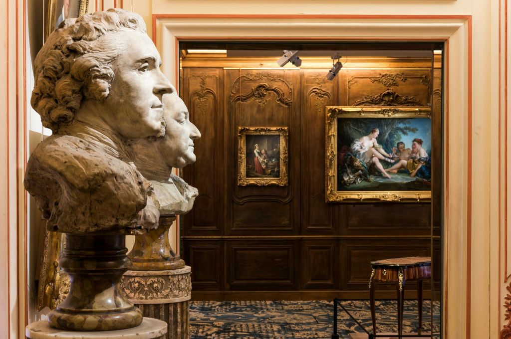 액자로 장식된 그림과 고급스러운 장식으로 장식된 화려한 방에서 역사적인 인물들의 돌 흉상을 볼 수 있습니다.