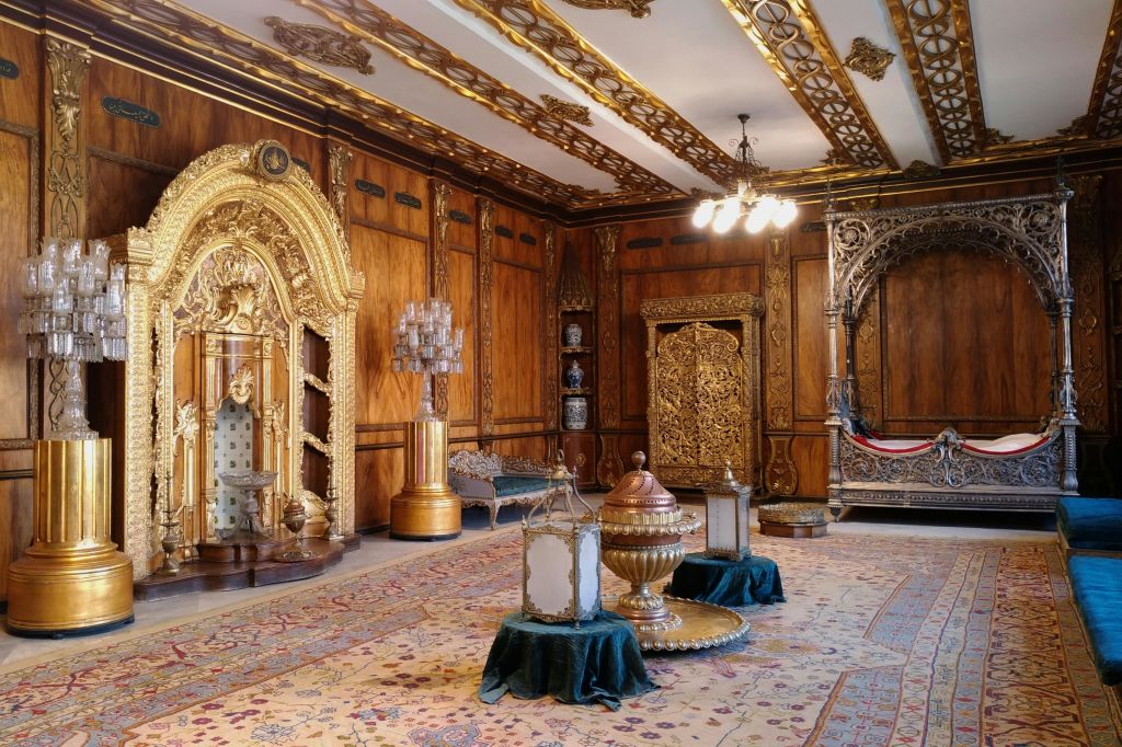 정교한 카펫 위에 정교한 골드 장식, 샹들리에, 고급스러운 가구가 놓인 화려한 객실.