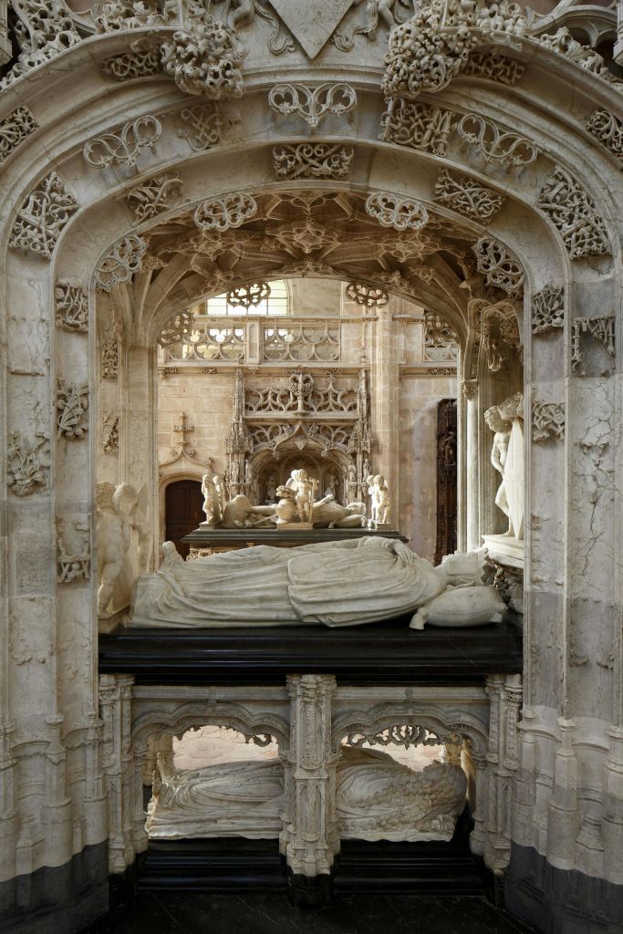 고딕 양식의 대성당 내부에 세밀한 조각과 조각상이 있는 화려한 석조 무덤이 있습니다.