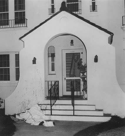 계단, 아치형 출입구, 흰색 외부가 있는 집 입구의 흑백 사진입니다.