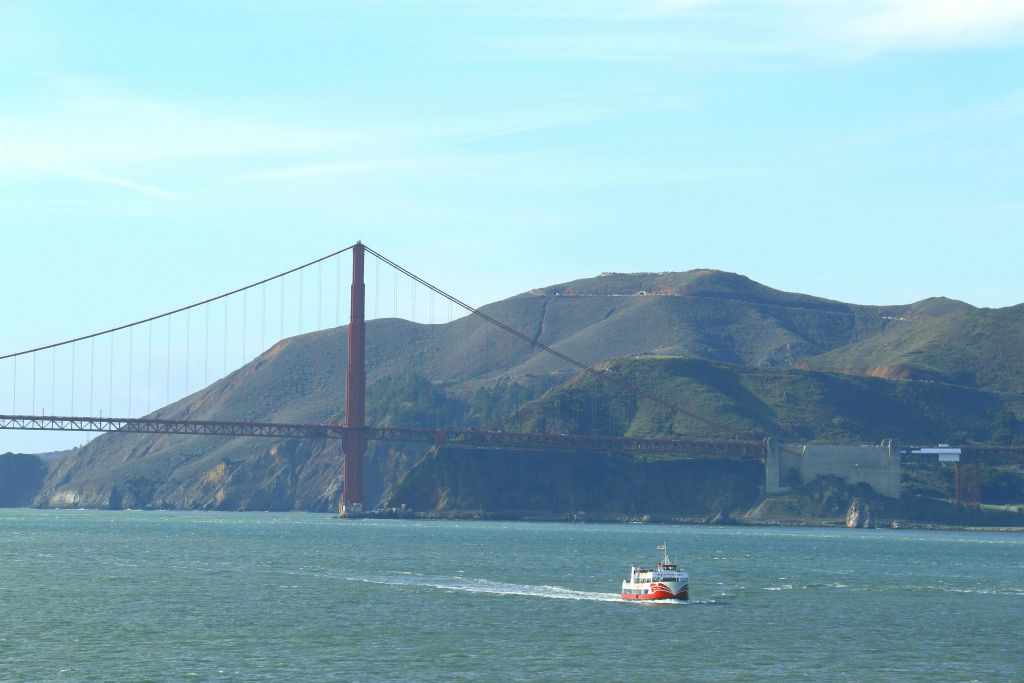 금문교가 있는 물 위의 보트와 맑은 하늘을 배경으로 언덕 풍경이 펼쳐집니다.
