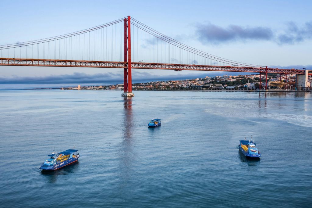 붉은 현수교를 배경으로 한 잔잔한 강에서 세 척의 투어 보트를 타고 강둑에서 도시 풍경을 감상해보세요.