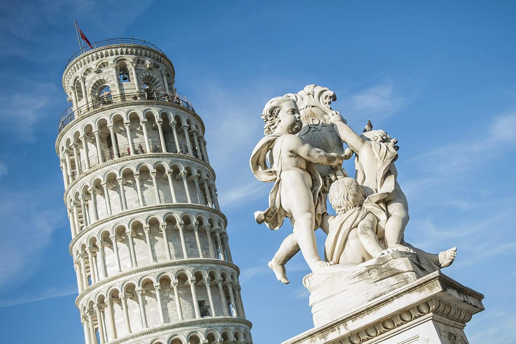 맑고 푸른 하늘 아래 피사의 사탑 앞에 있는 세 그룹의 하얀 대리석 동상.