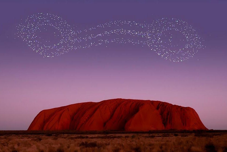 자줏빛 하늘 아래 커다란 붉은 바위 지층, 그 위에는 밝은 별들이 소용돌이치는 무늬를 이루고 있다.