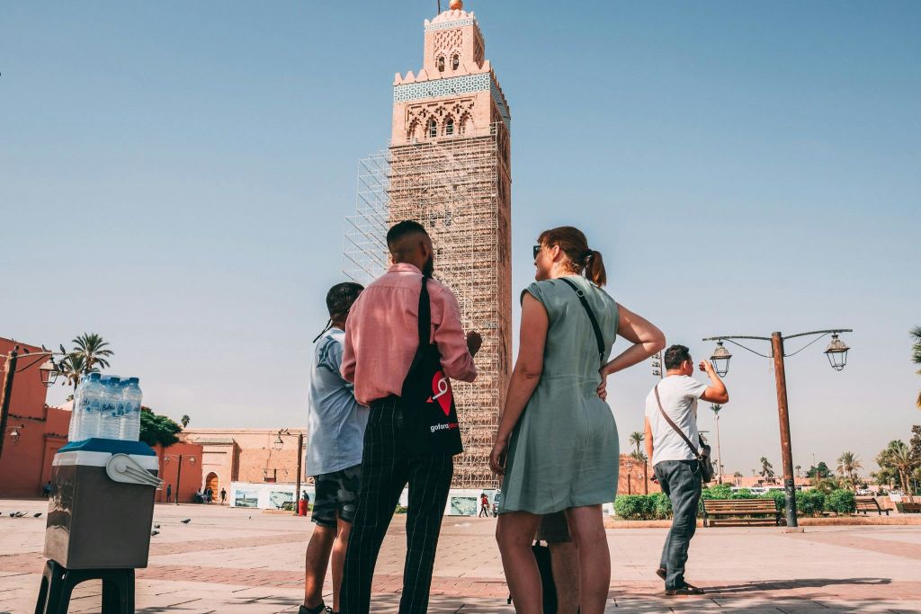 맑은 날 비계로 덮인 높은 탑 앞에 서서 대화를 나누는 사람들.