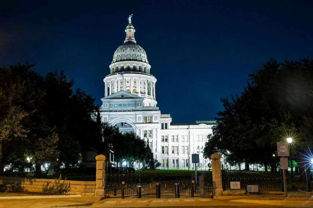 밤에는 커다란 흰색 국회의사당 건물이 건물 전면에 불빛을 비춥니다.