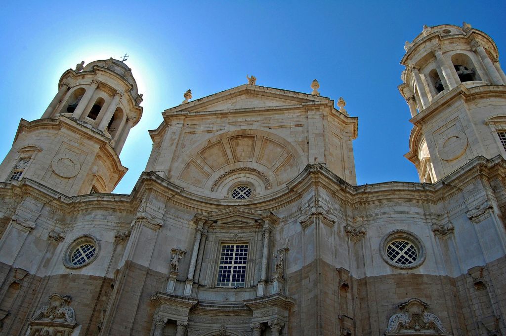 맑고 푸른 하늘을 배경으로 두 개의 탑이 있는 웅장하고 화려한 석조 성당의 햇살 가득한 외관.
