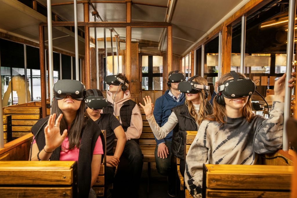 가상 현실 헤드셋을 착용한 나무 트램을 탄 승객이 손을 뻗어 미소를 짓고 있습니다.