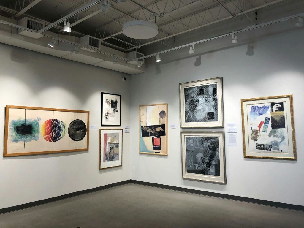 천장의 스포트라이트 아래 하얀 벽에 액자 모양의 추상적인 그림이 있는 미술관입니다.