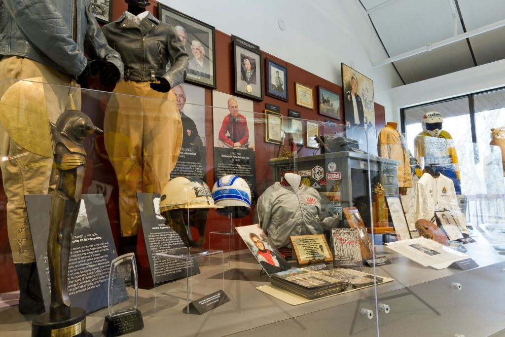 재킷, 헬멧, 명판, 사진, 정보 명판 등 항공 기념품을 전시하는 박물관 전시물입니다.