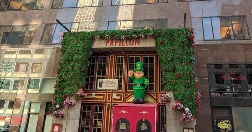 푸른 단풍과 꽃, 경쾌한 나뭇잎 형상으로 장식된 건물 입구로, 위에는 '빠삐용' 이라는 간판이 있습니다.