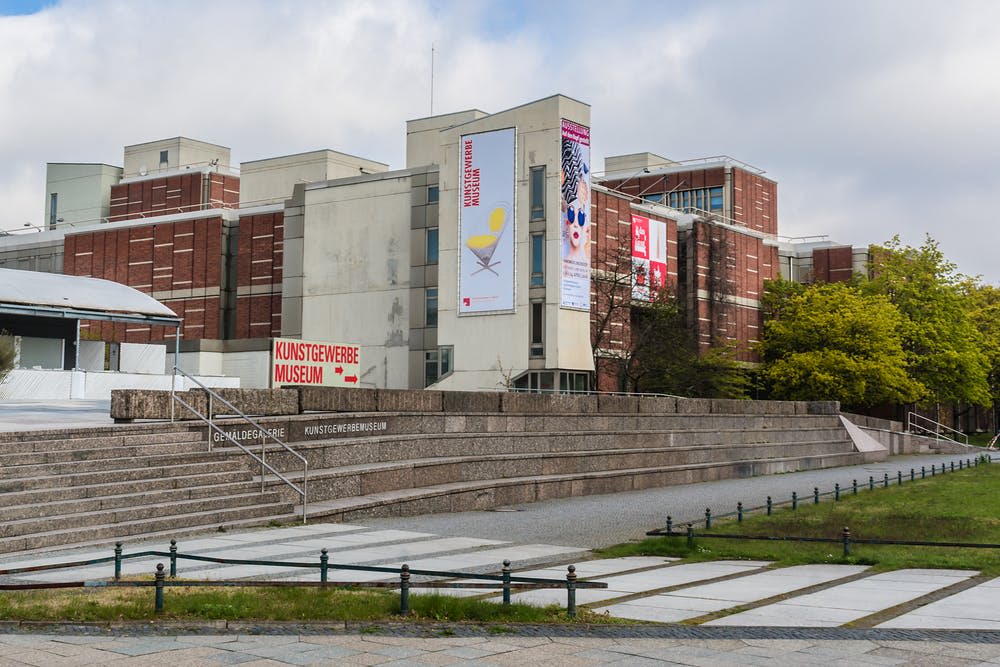 대형 배너와 간판이 있는 현대적인 벽돌 및 콘크리트 건물인 Kunstgewerbemuseum의 외관.