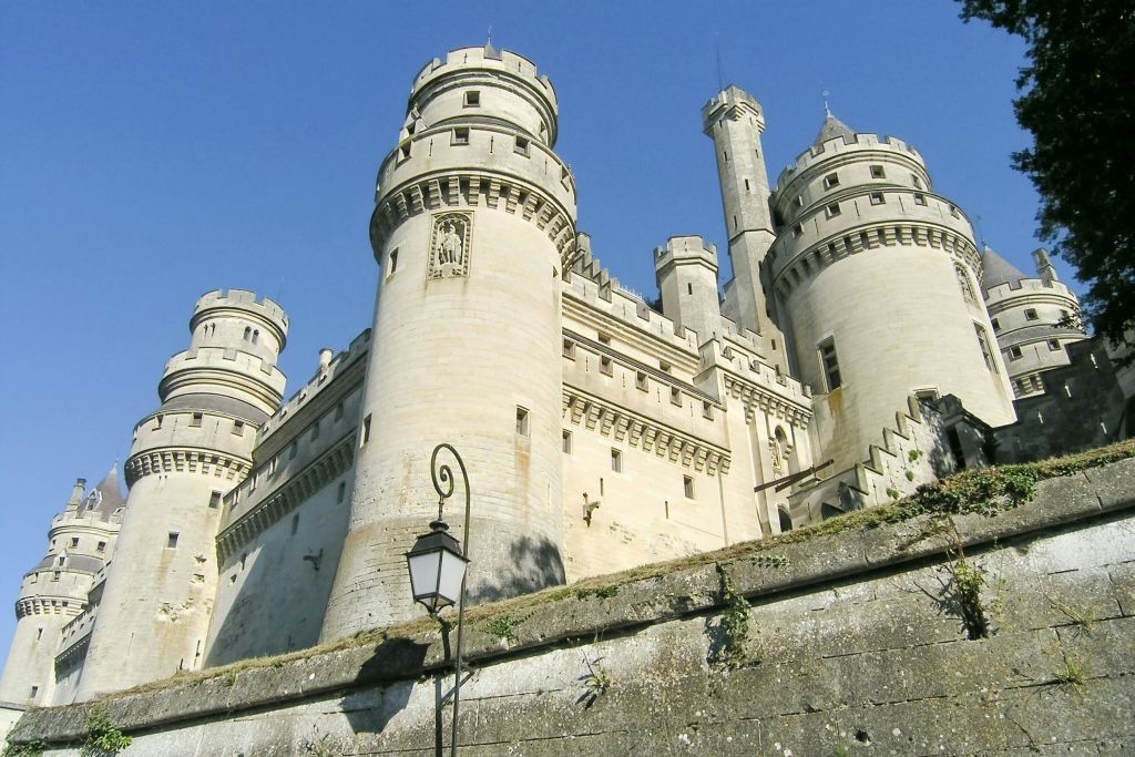 둥근 탑이 있는 석조 성, 맑고 푸른 하늘을 배경으로 한 고풍스러운 전등 기둥.