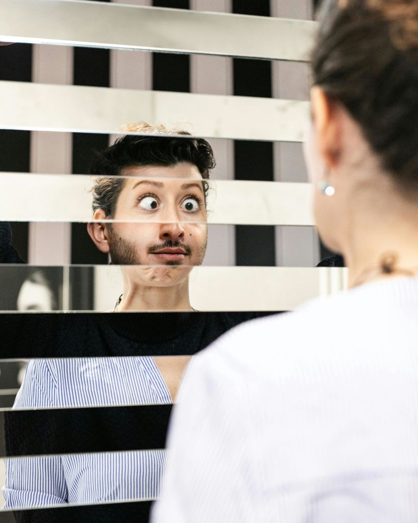 엇갈린 패널 거울에 비친 유머러스한 표정의 인물이 얼굴의 왜곡된 모습을 연출합니다.