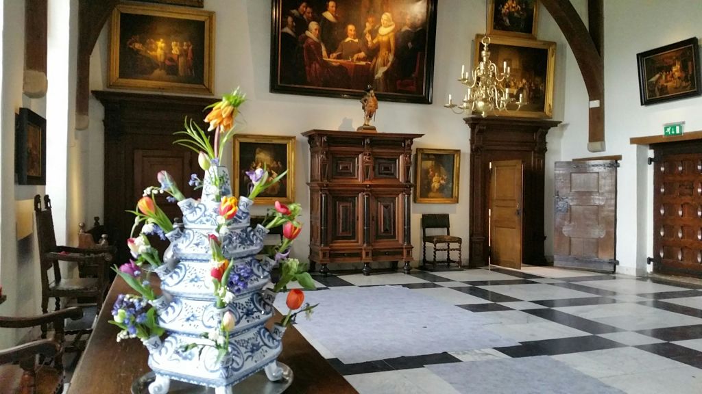 고전적인 그림, 샹들리에, 목재 가구가 있는 우아한 방의 테이블에는 장식용 도자기 꽃꽂이가 놓여 있습니다.