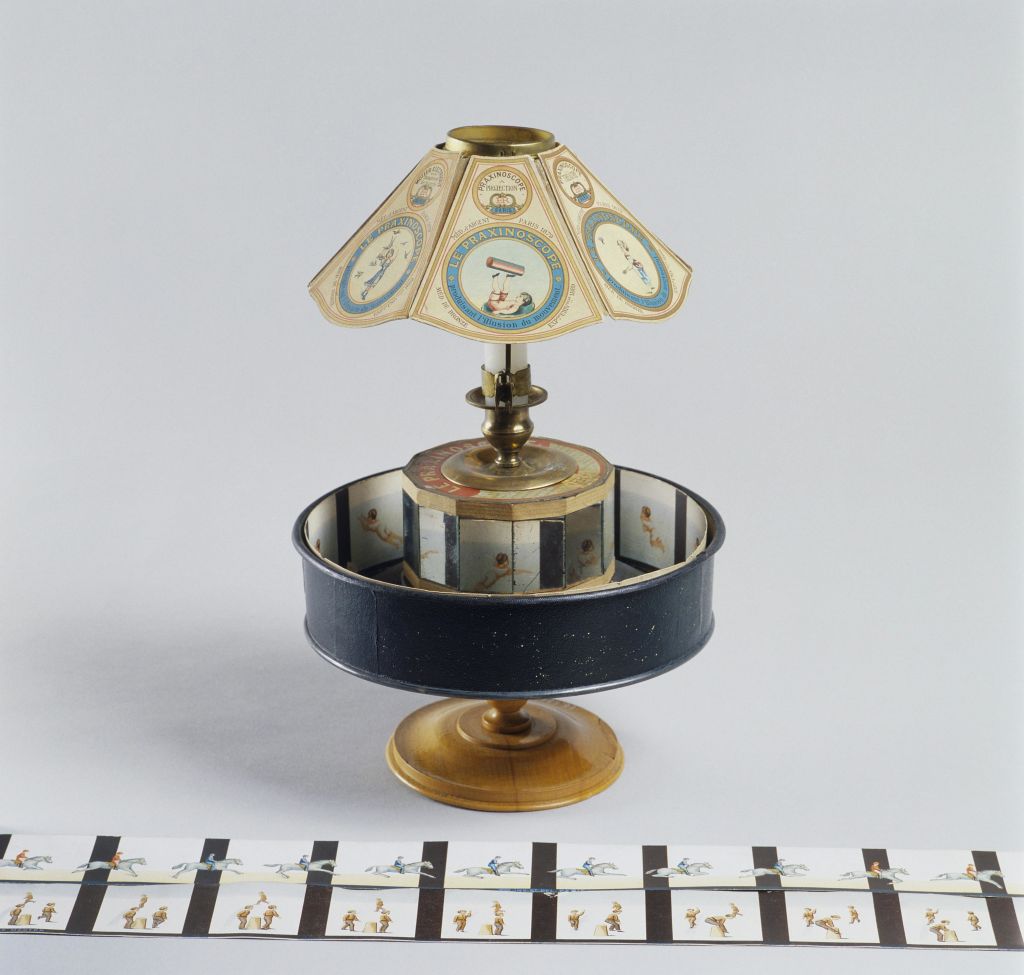 애니메이션 비주얼을 만들기 위한 것으로 추정되는 일련의 이미지를 보여주는 일러스트 종이 스트립이 있는 스탠드의 빈티지 조이트로프.