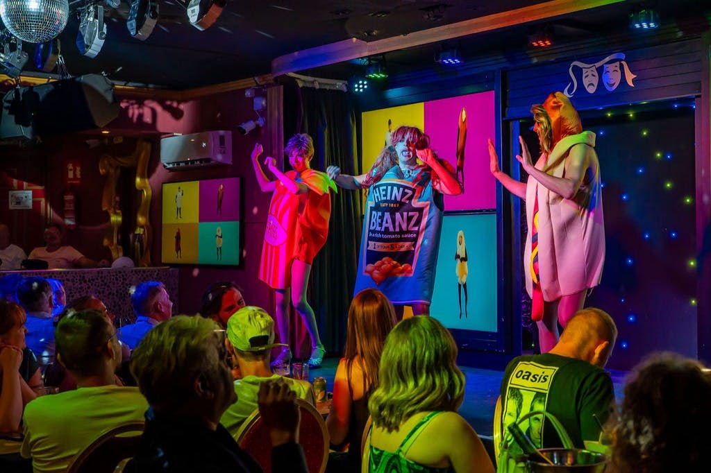 다채로운 무대에서 음식 아이템을 닮은 의상을 입은 공연자들이 전경에 관객을 앉혔습니다.