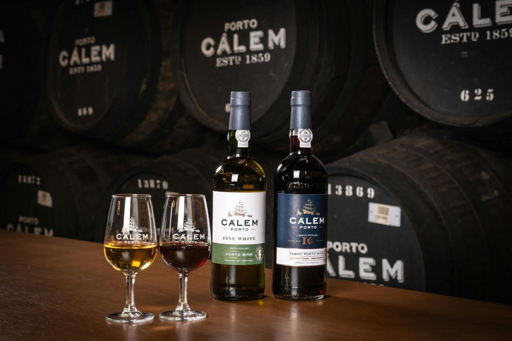 칼렘 포르투 와인 두 병, 화이트와 레드 와인 한 잔, 통을 배경으로.
