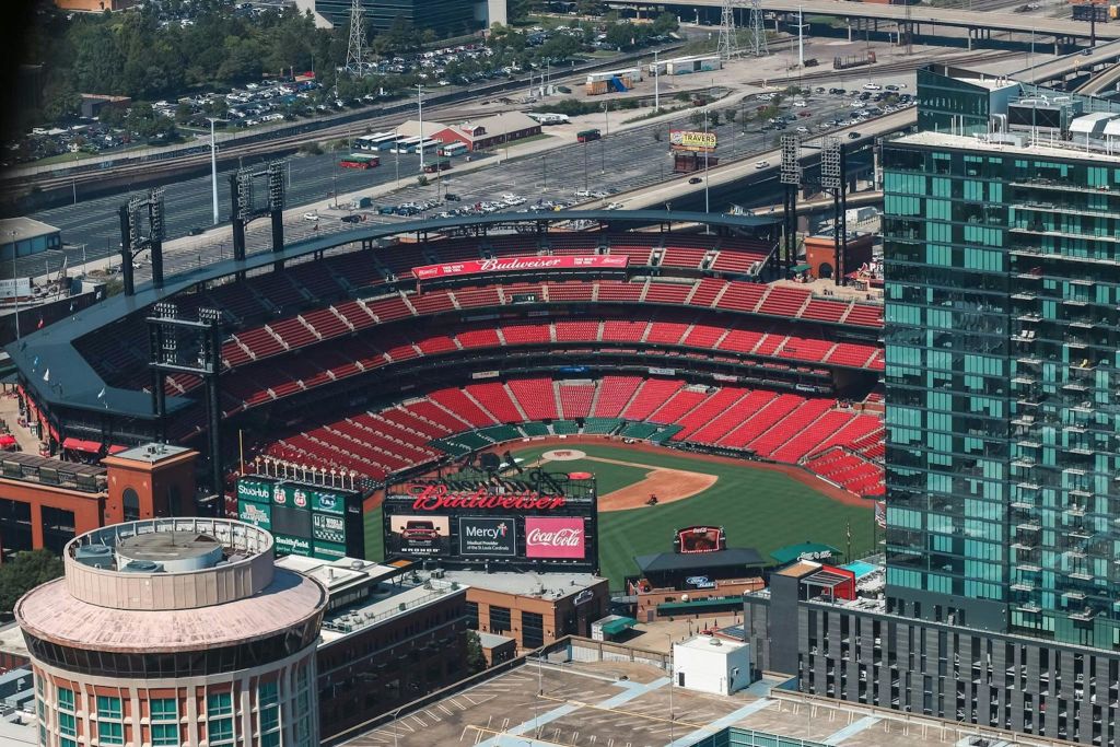 빨간색 좌석, 녹색 필드 및 주변 도시 건물이 있는 빈 야구 경기장의 공중 전망.