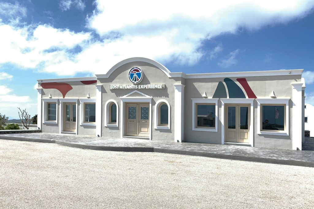 입구 위에 "잃어버린 아틀란티스 체험" 이 있는 밝은 색상의 건물로, 아치형 출입구와 화려한 벽 액센트가 특징입니다.