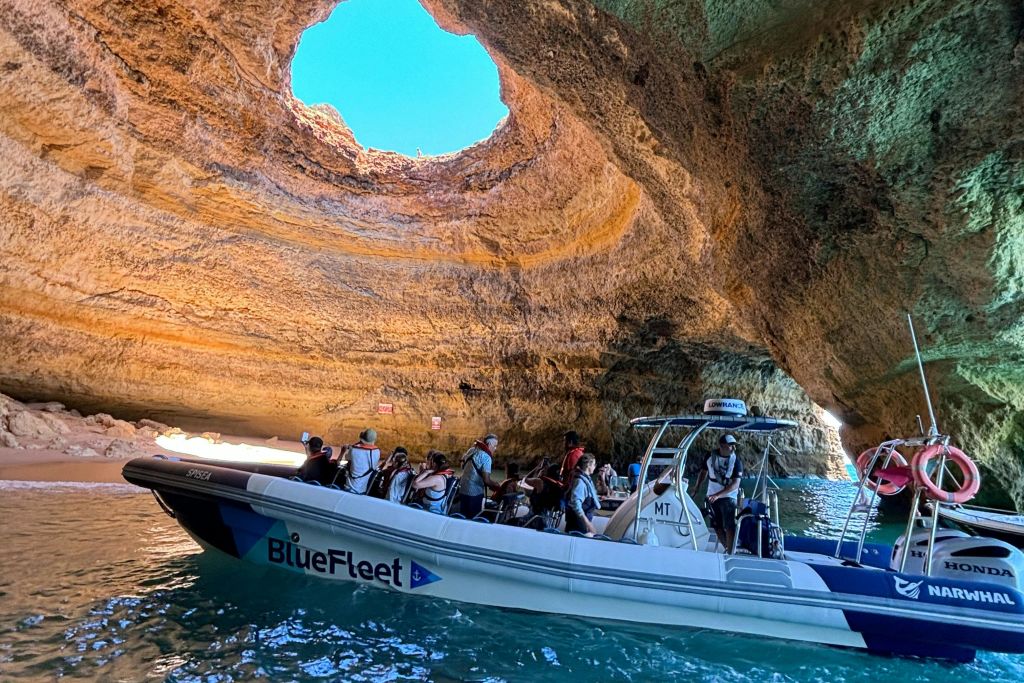 상단에 커다란 개구부가 있는 자연 동굴 안에 승객이 타고 있는 보트로, 햇빛이 현장을 비출 수 있습니다.