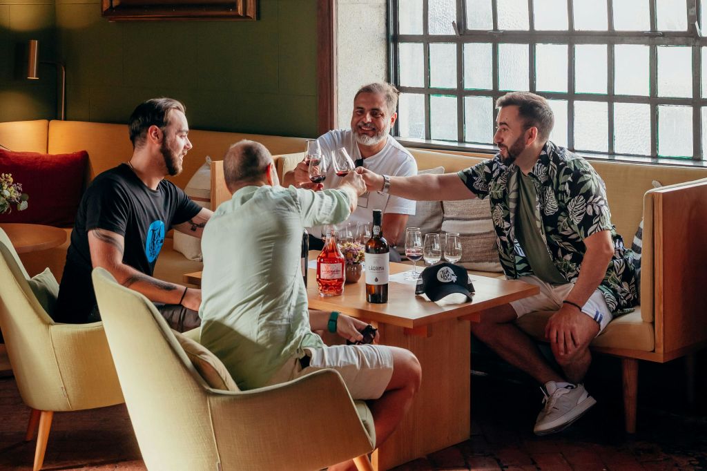 아늑한 분위기에서 테이블에 앉은 네 명의 남성이 안경을 끼고 함께 음료를 즐기고 있습니다.