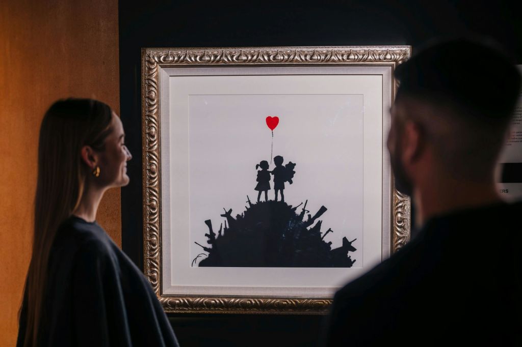 흐릿한 커플이 감탄하는 뱅크시 프린트.