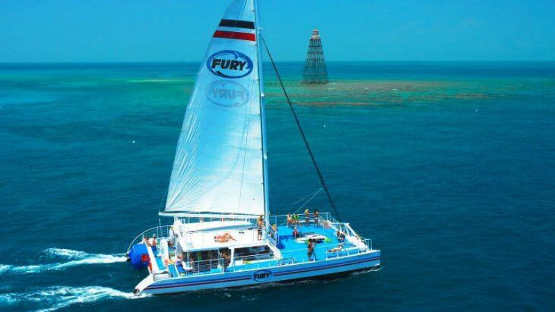 '퓨리 (Fury)' 라는 이름의 범선이 저 멀리 보이는 항해용 마커 구조물과 함께 맑고 푸른 바다를 항해합니다.