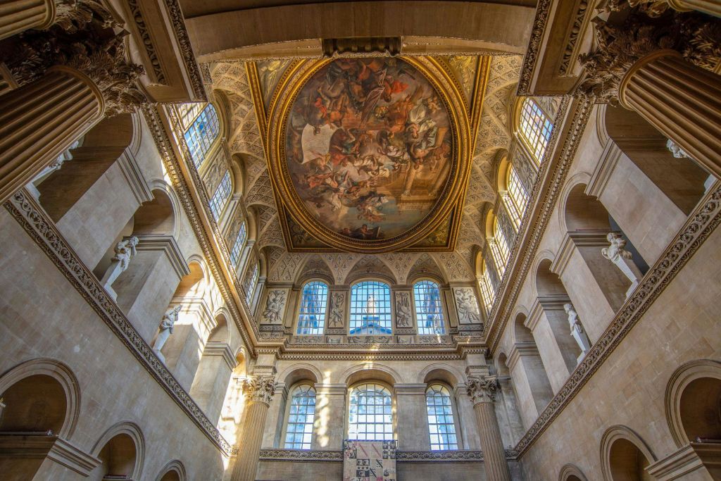 높은 아치형 창문, 장식된 벽, 정교한 장면을 묘사한 크고 디테일한 천장 프레스코가 있는 화려한 홀.