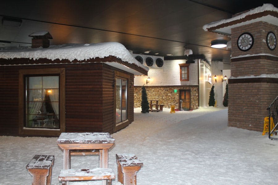 나무 오두막, 소나무, 벤치가 있는 눈 덮인 실내 풍경. 아늑하고 겨울 분위기가 물씬 풍기는 숙소입니다.