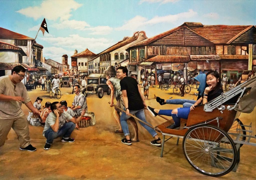 사람들은 역사적인 거리 시장 벽화와 상호 작용하며 카트를 끄는 포즈를 취하고 척합니다.