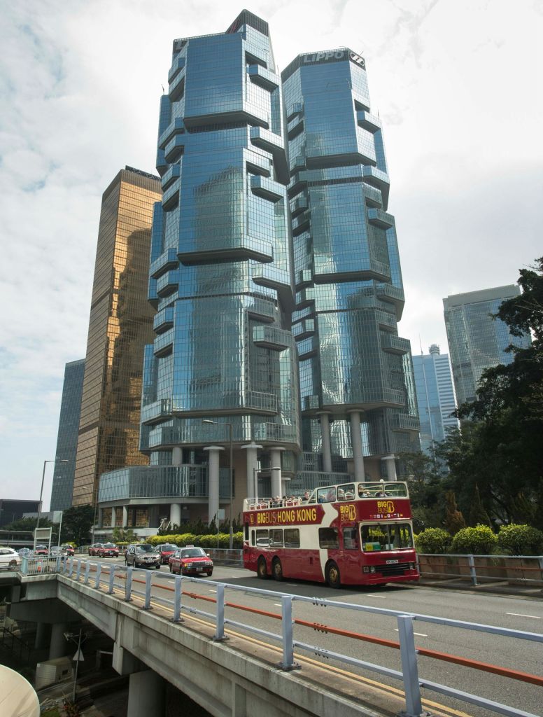 현대적인 유리 고층 건물과 다른 차량이 있는 도로에 빨간색 이층 버스가 있습니다.