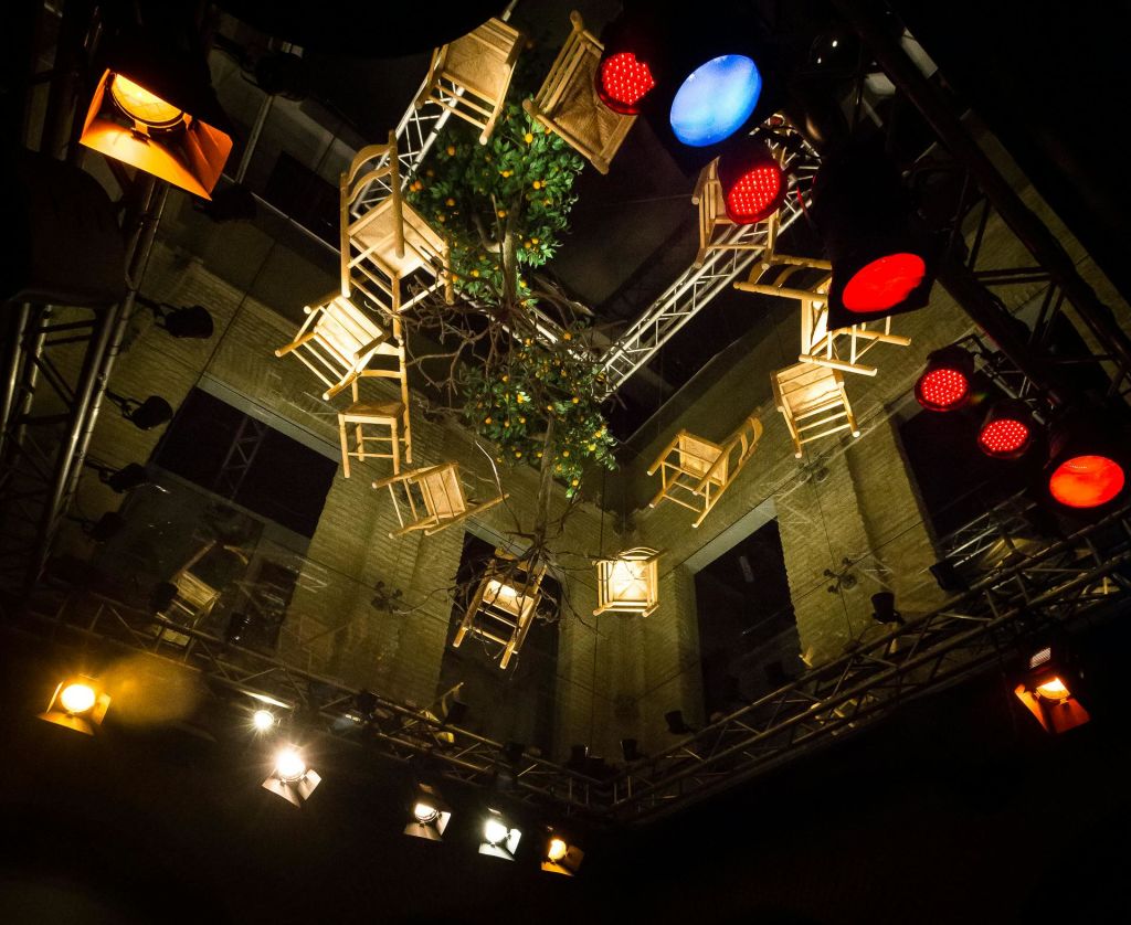 화려한 무대 조명이 있는 천장에는 나무 의자와 푸른 나무가 거꾸로 매달려 있습니다.