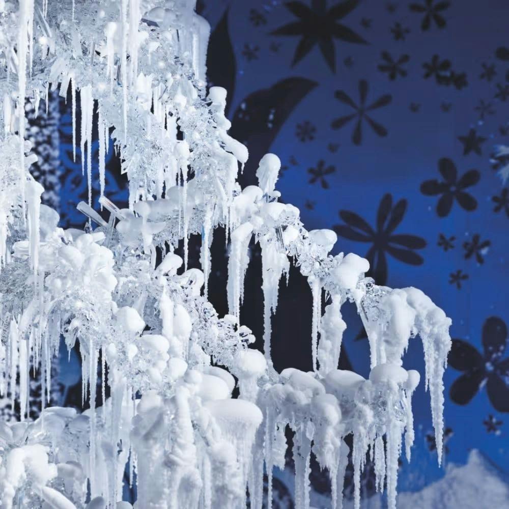 꽃 무늬가 있는 파란색 배경에 고드름으로 덮인 얼어붙은 나무 가지.