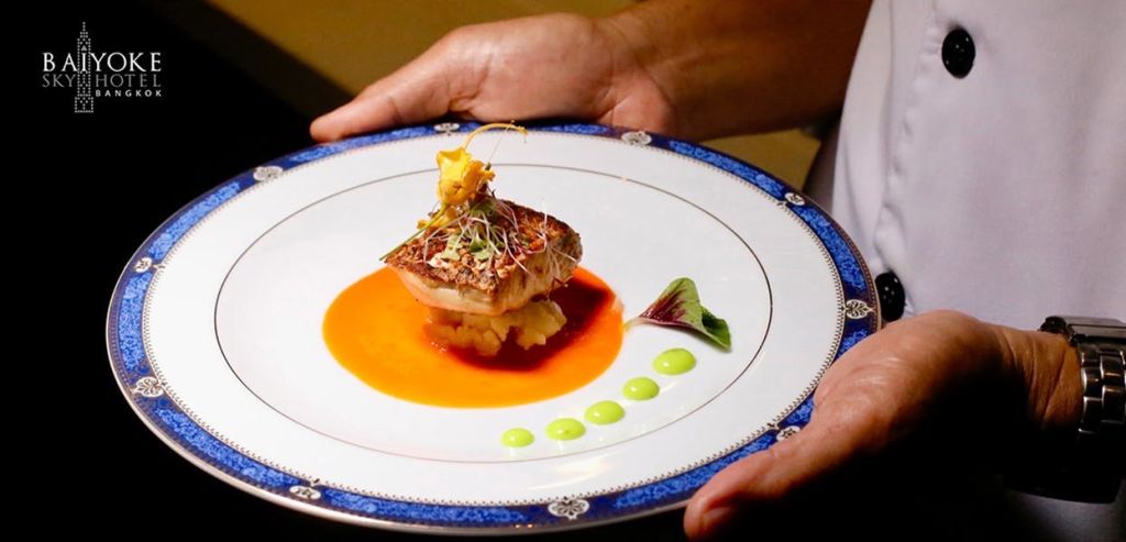 미식가 생선 요리가 담긴 장식용 접시를 들고 마이크로그린으로 장식하고 다채로운 소스를 곁들입니다.