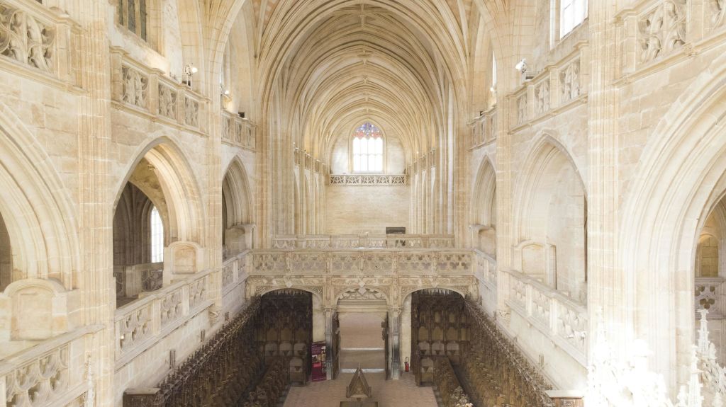 높은 아치형 천장, 정교한 석조물, 목조 성가대가 있는 넓은 고딕 양식의 성당 내부.