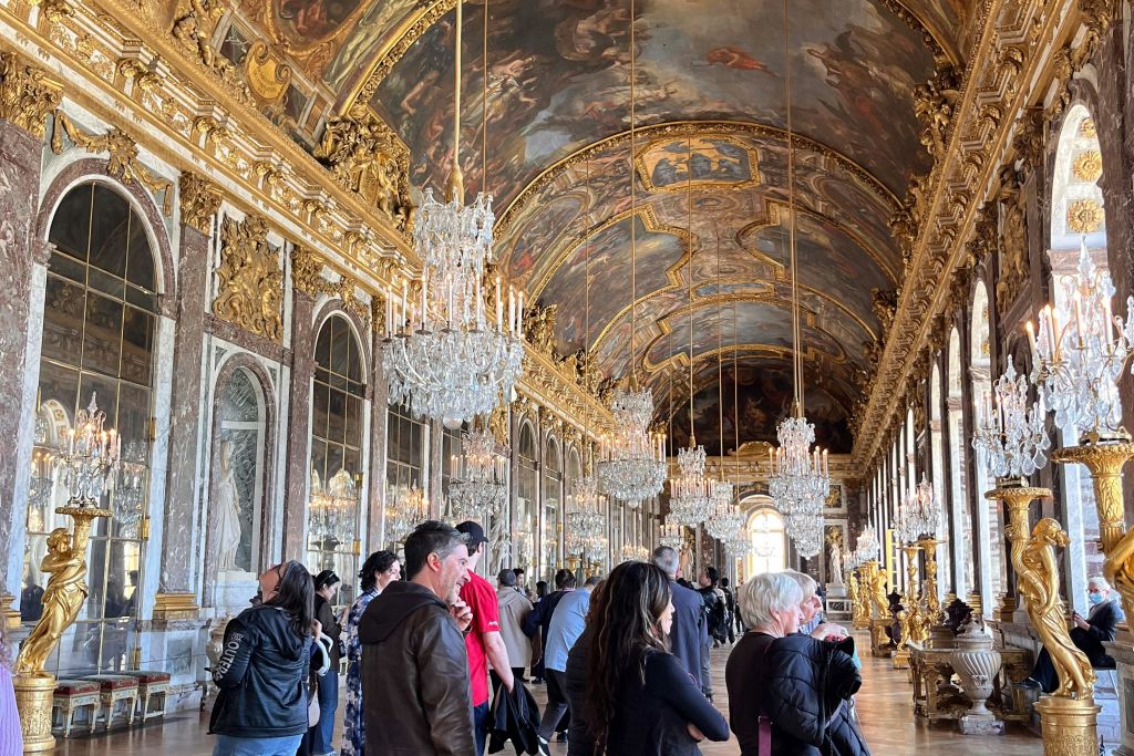 샹들리에와 화려한 장식으로 둘러싸인 베르사유 궁전 거울의 전당에 모인 관광객들.