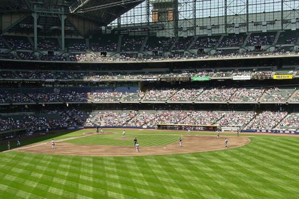 부분적으로 개방된 지붕이 있는 대형 경기장에서 진행 중인 야구 경기로 관중들이 스탠드를 채우고 있습니다.