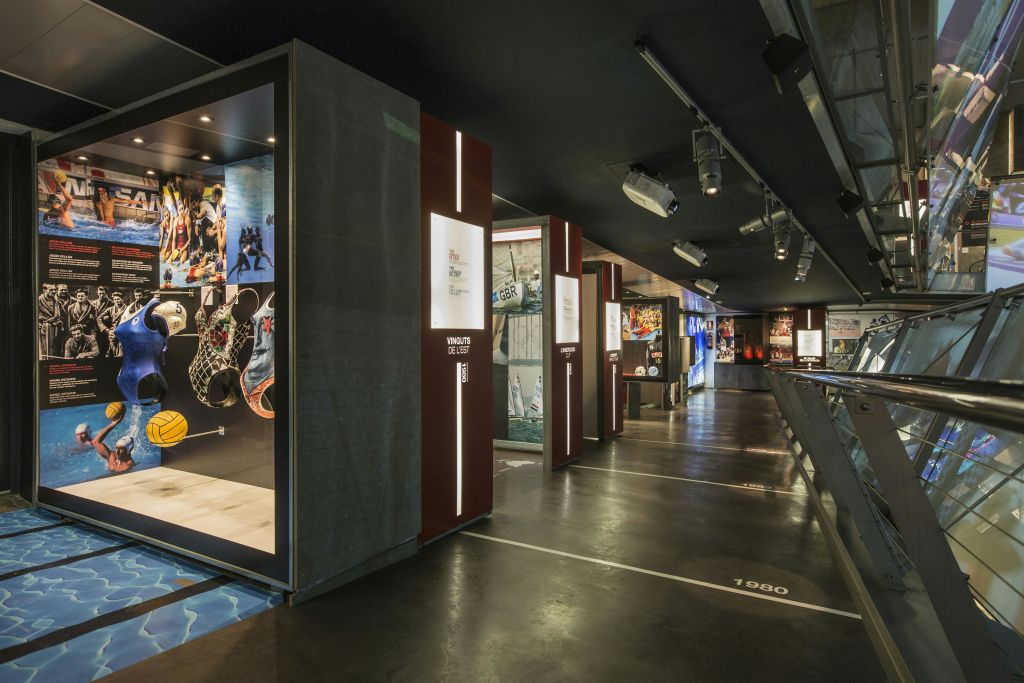 바닥에 타임라인 표시, 조명 디스플레이 케이스 및 다양한 정보 패널이 있는 전시장.