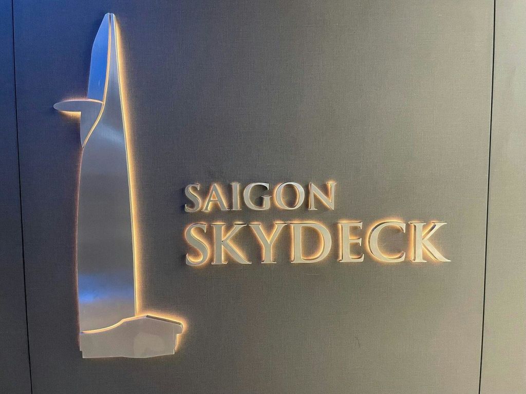 '사이공 스카이덱 (Saigon Skydeck)' 이라는 조명 텍스트와 건물의 양식화된 묘사로 사인을 해보세요.