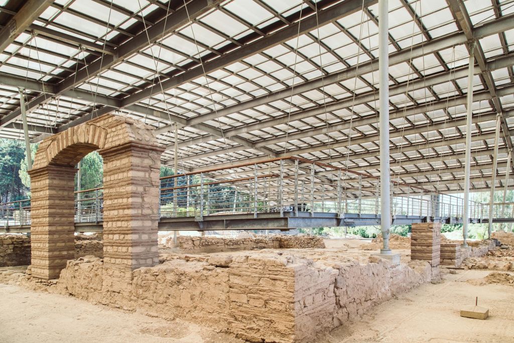 현대적인 금속과 유리 지붕 아래 벽돌 구조가 돋보이는 고대 유적지로, 통로가 높이 솟아 있습니다.