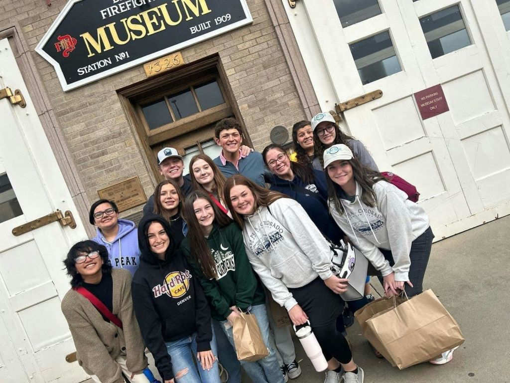 1번 스테이션인 소방관 박물관 앞에서 미소와 캐주얼한 복장을 한 사람들이 포즈를 취하고 있습니다.