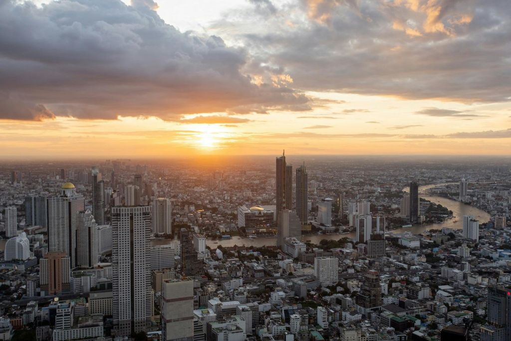 구름을 배경으로 석양을 배경으로 수많은 고층 건물이 있는 석양의 도시 풍경.