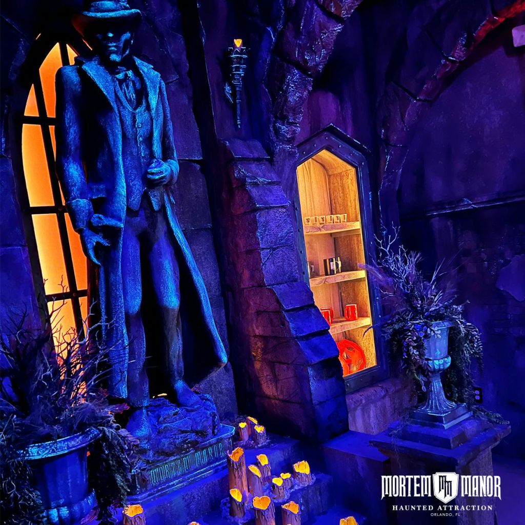 모자를 쓴 남자의 동상이 있는 희미한 고딕 양식의 방. 책과 물약이 담긴 선반. 주변의 섬뜩한 조명과 촛불.