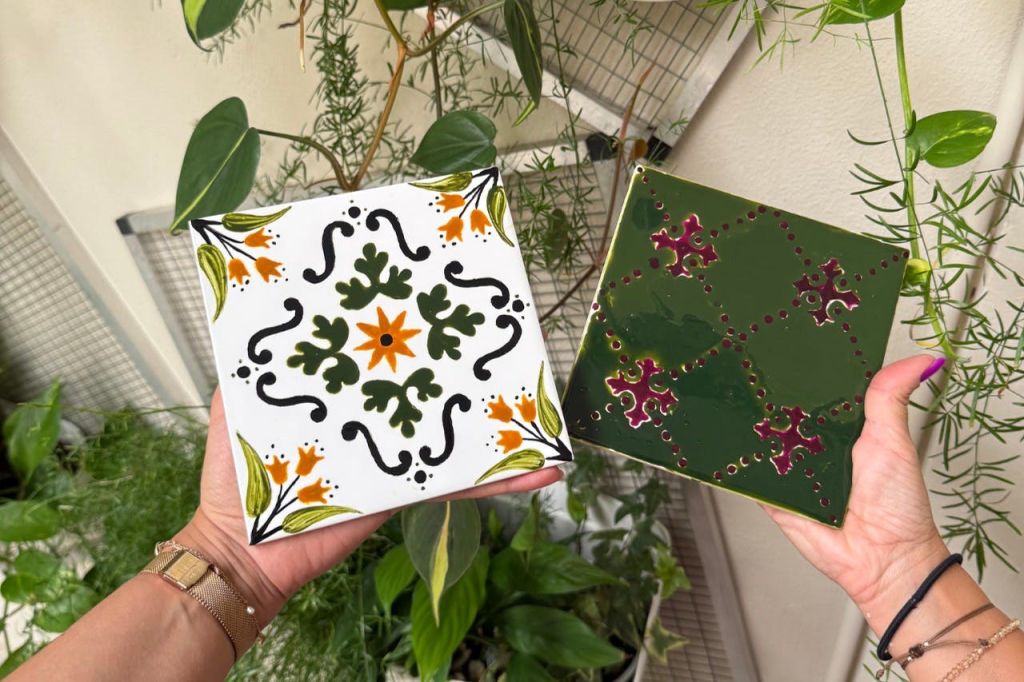 장식 패턴이 있는 두 개의 세라믹 타일, 꽃을 모티브로 한 흰색 타일, 손으로 잡은 기하학적 디자인의 녹색 타일.