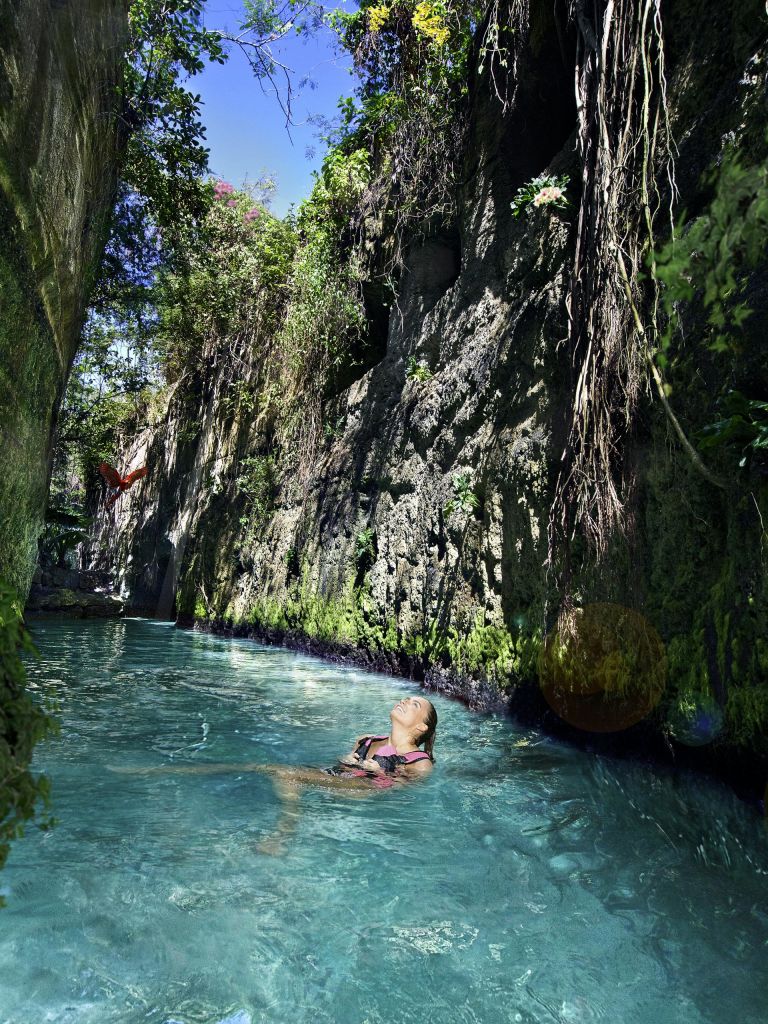 한 사람이 초목이 우거진 높은 바위 절벽에 둘러싸인 맑고 푸른 물에 떠 있습니다. 왼쪽에 붉은 나비가 보입니다.