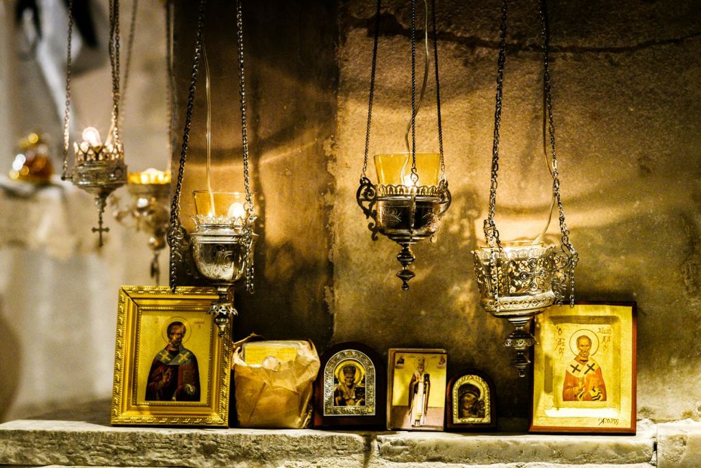 선반에 성도 아이콘 위에 화려한 램프를 걸고 왼쪽에는 낡은 종이 봉투, 오른쪽에는 액자 모양의 성도 이미지가 놓여 있습니다.