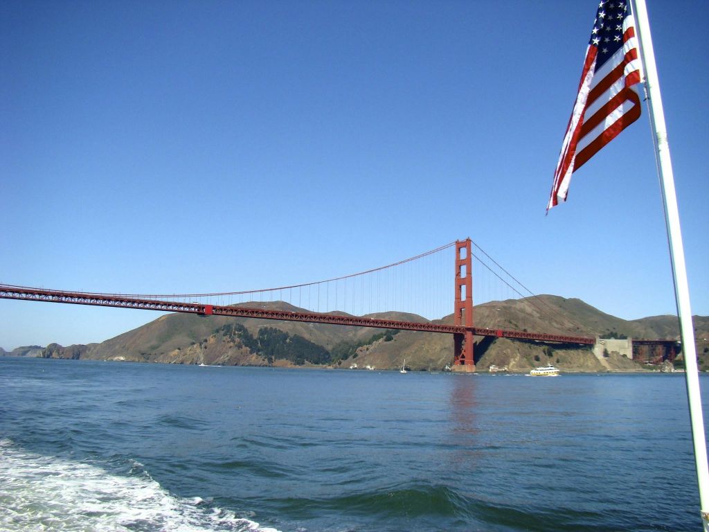 맑은 날 물 위로 보이는 금문교의 전경에는 미국 국기가 새겨져 있습니다.