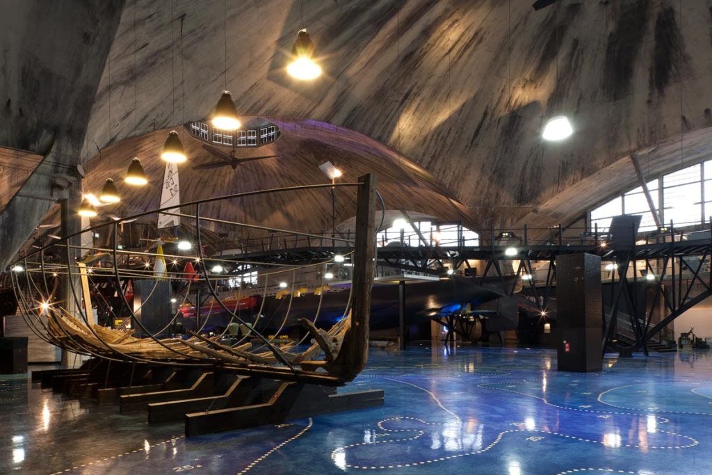 어두운 조명과 커다란 곡선형 천장이 있는 오래된 목조 선박 프레임이 전시된 박물관 내부.