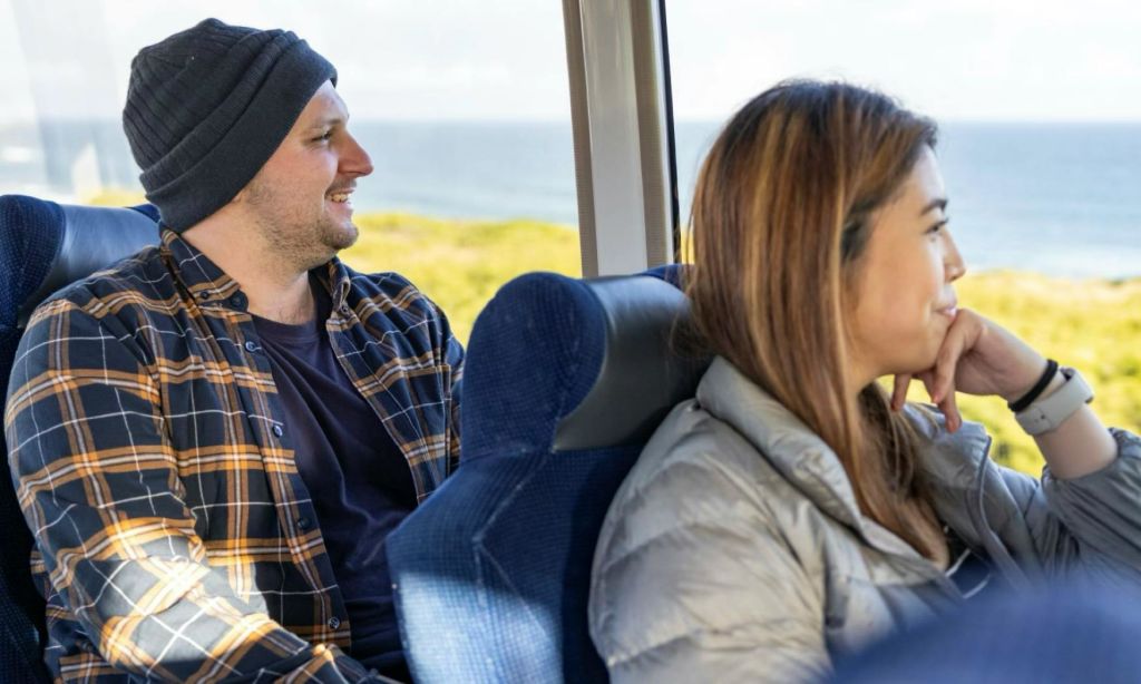 두 사람이 움직이는 차량에 앉아 창문을 통해 보이는 아름다운 바다 전망을 감상하고 있습니다.